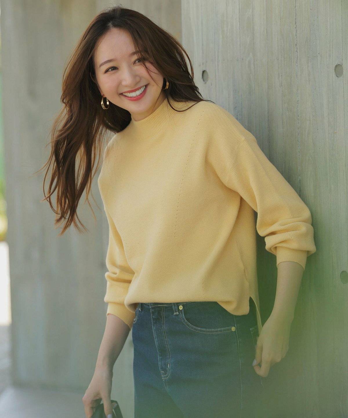 イエローのニットにデニムパンツを合わせた女性