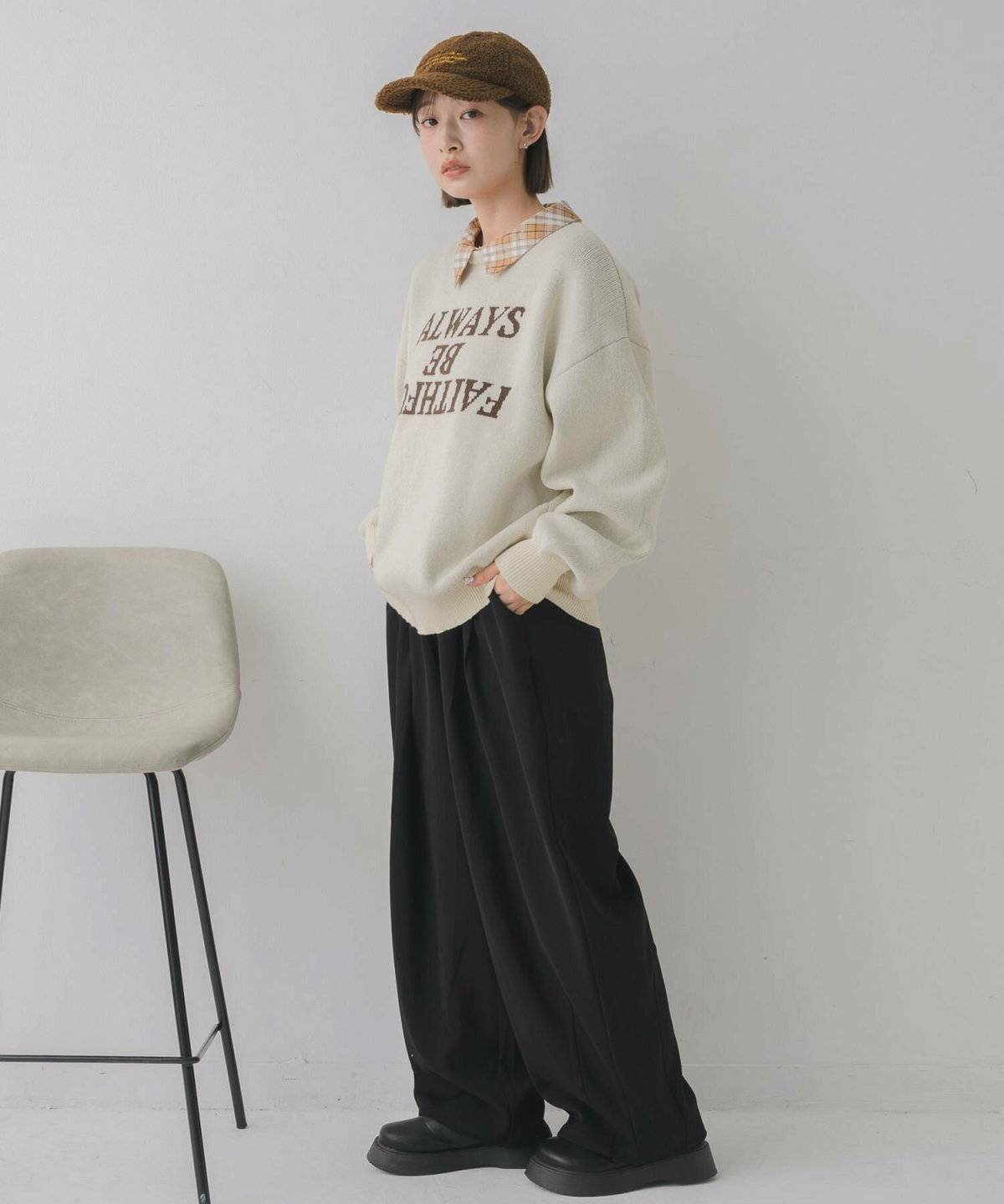 ベージュのニットに黒のニットパンツを合わせた女性