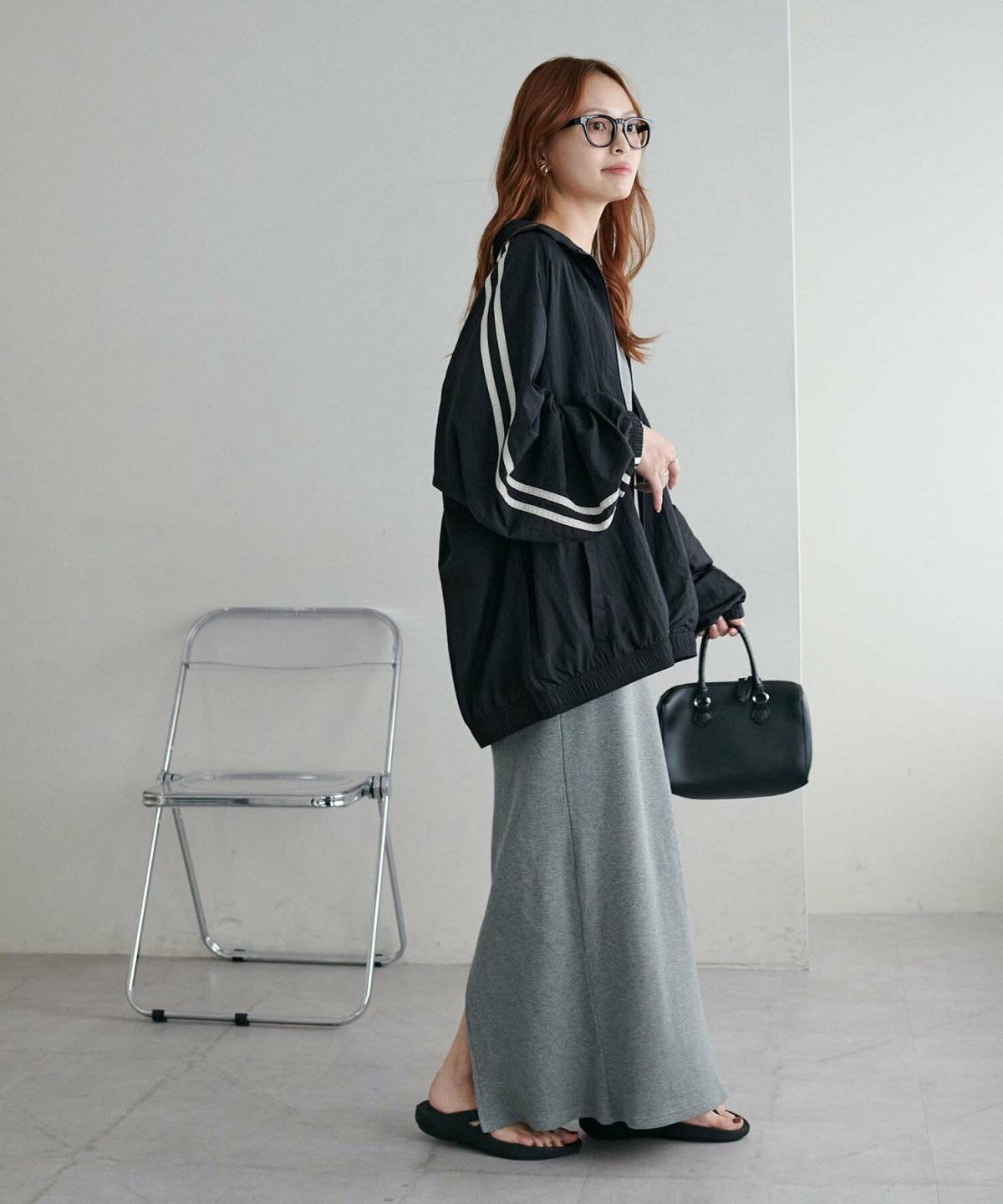 ネイビーのトラックジャケットにグレーのスカートを合わせた女性