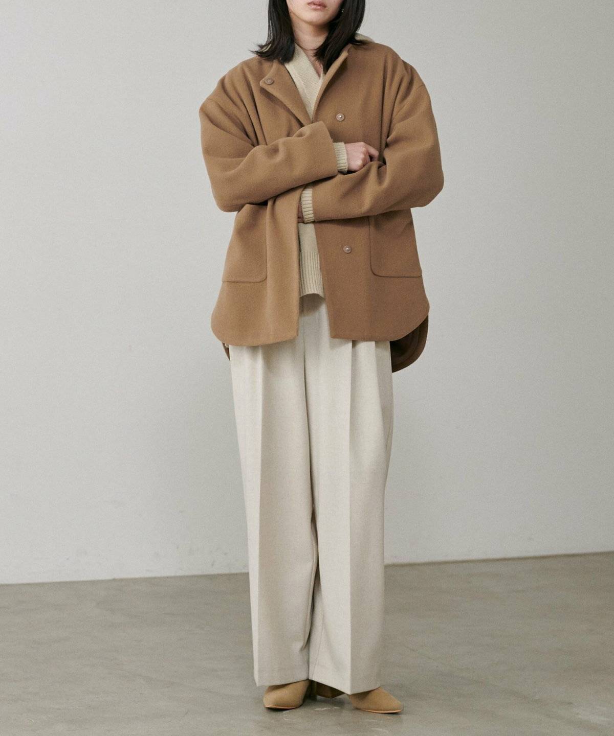 ホワイトコーデにモカのコートを羽織った女性