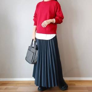  赤ニットにグレーのスカートを合わせた女性 