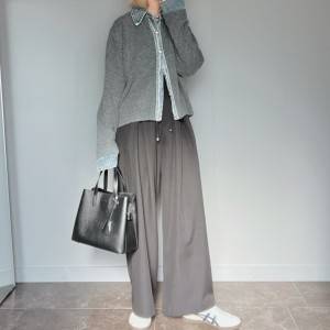  グレーのカーディガンに黒パンツを合わせた女性 