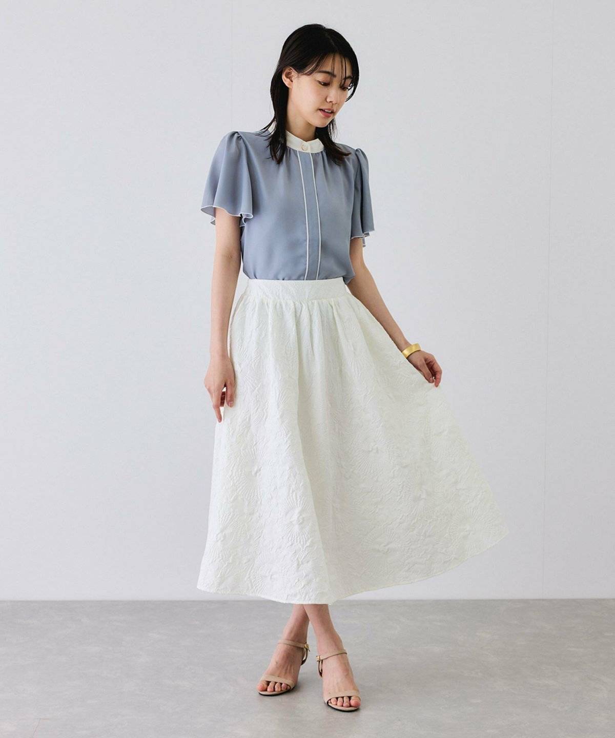 シャツにジャガードスカートを合わせた女性