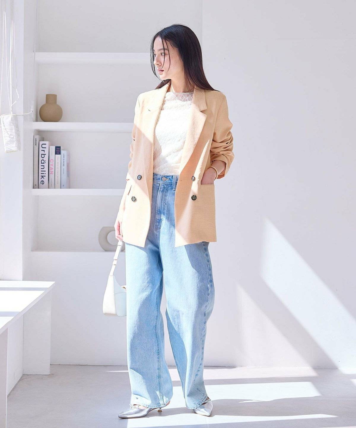 オレンジのジャケットにベージュのパンツを合わせた女性