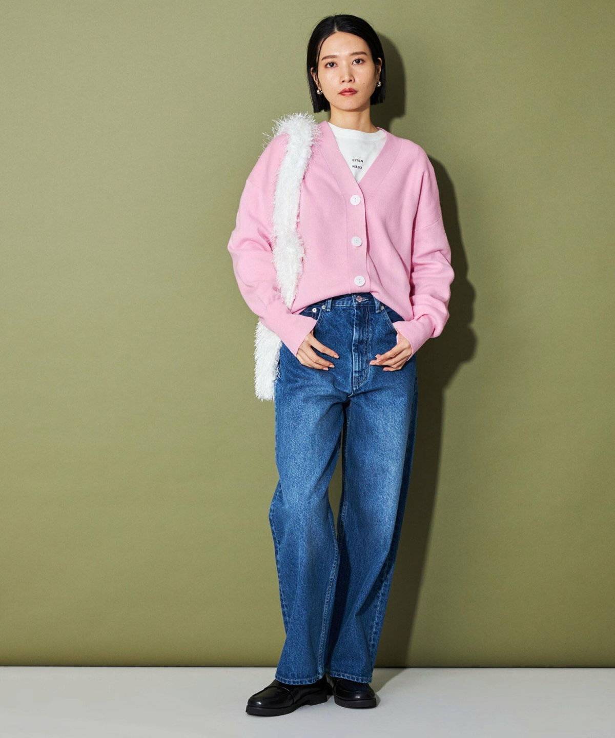 モノトーンコーデにピンクのカーディガンを肩掛けした女性