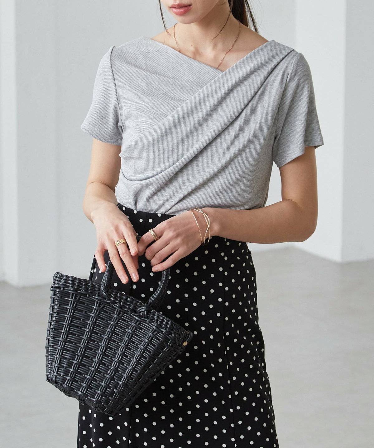 グレーのトップスに黒スカートを合わせた女性