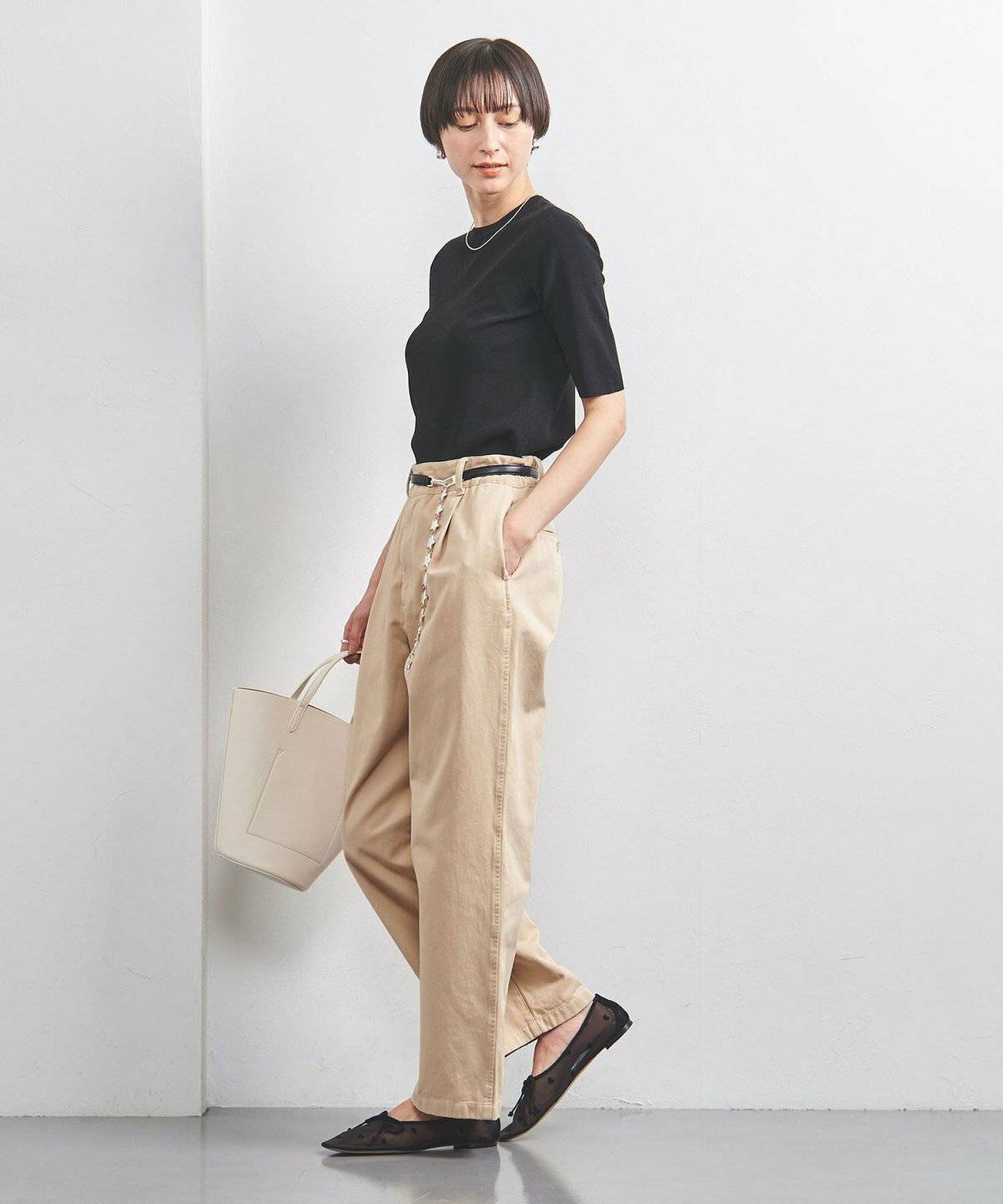 黒トップスにベージュのパンツを合わせた女性