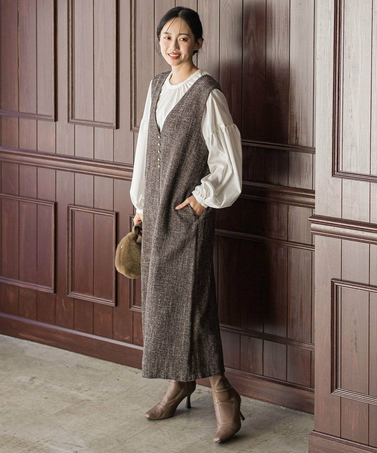 ベージュのブラウスにグレーのワンピースを合わせた女性