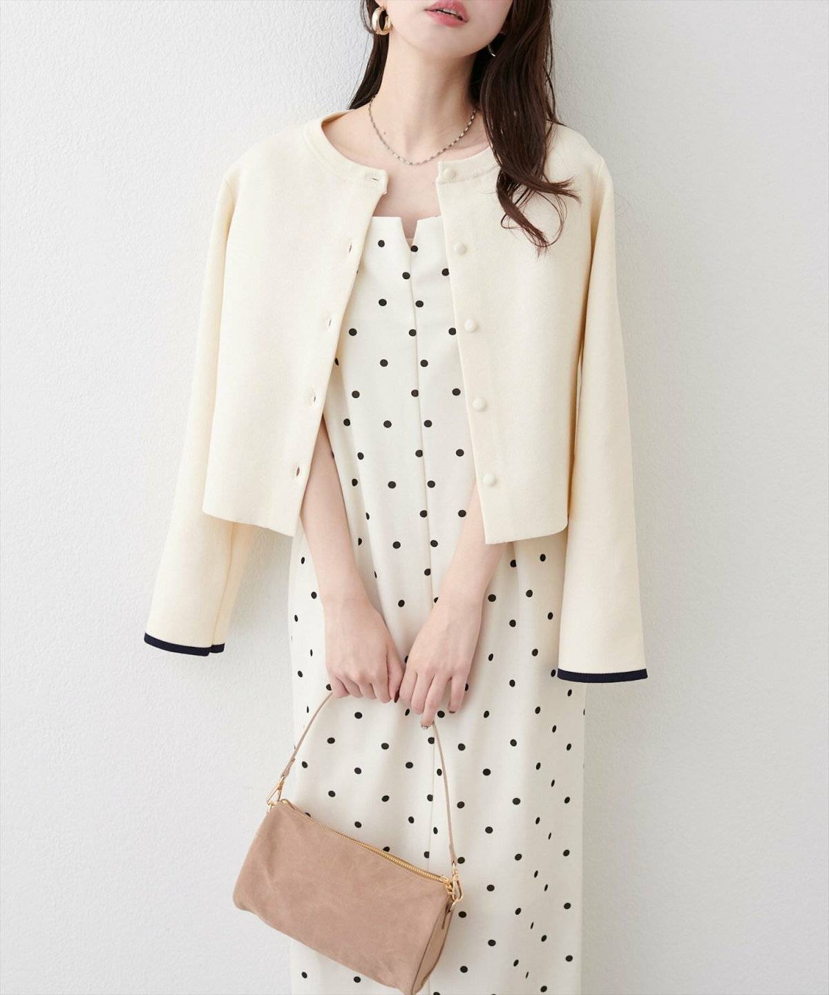 ベージュのワンピースにカーディガンを合わせた女性