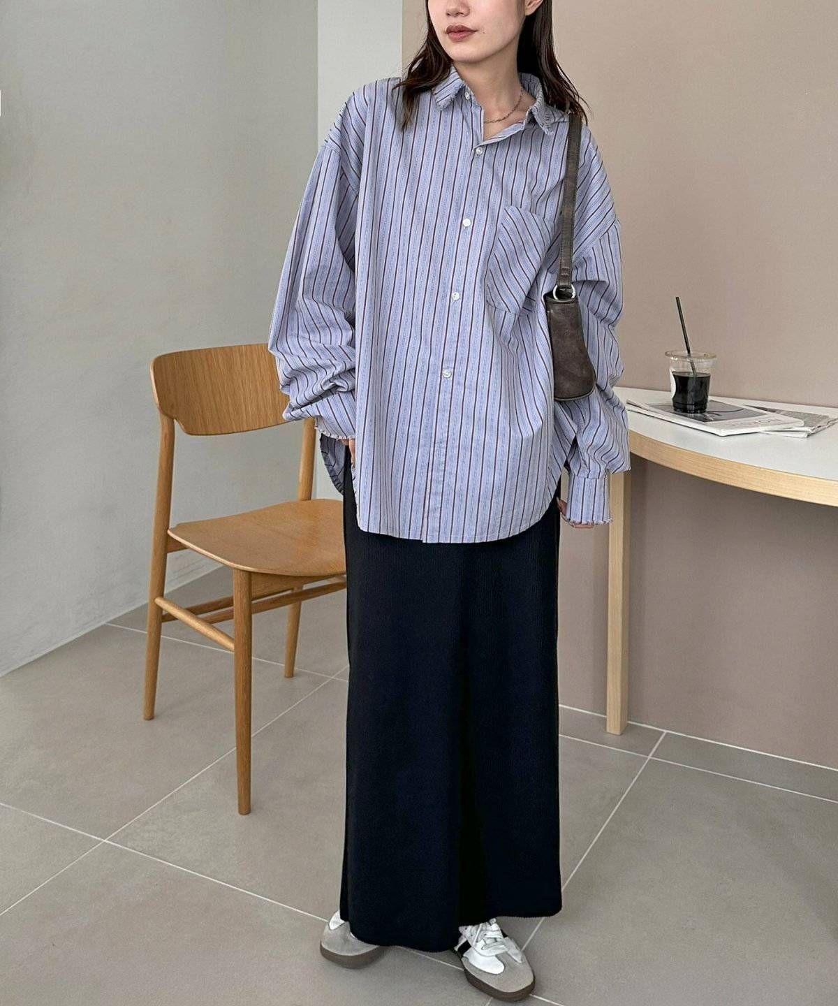 ストライプ柄のシャツに黒スカートを合わせた女性