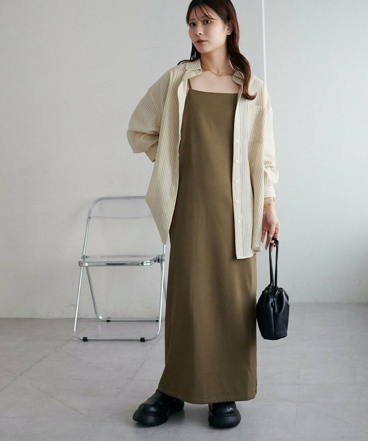 黒ワンピースにブルーのシャツを羽織った女性