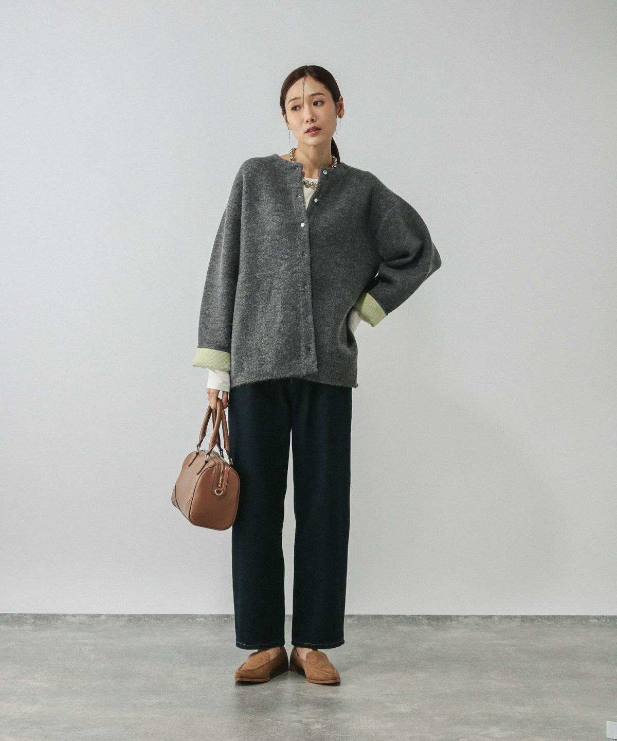 グレーのニットブルゾンに黒パンツを合わせた女性