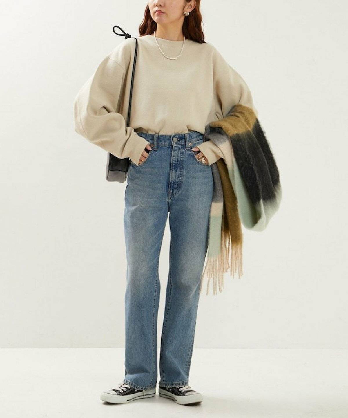 白スウェットにデニムを合わせてグレーのマフラーを巻いた女性