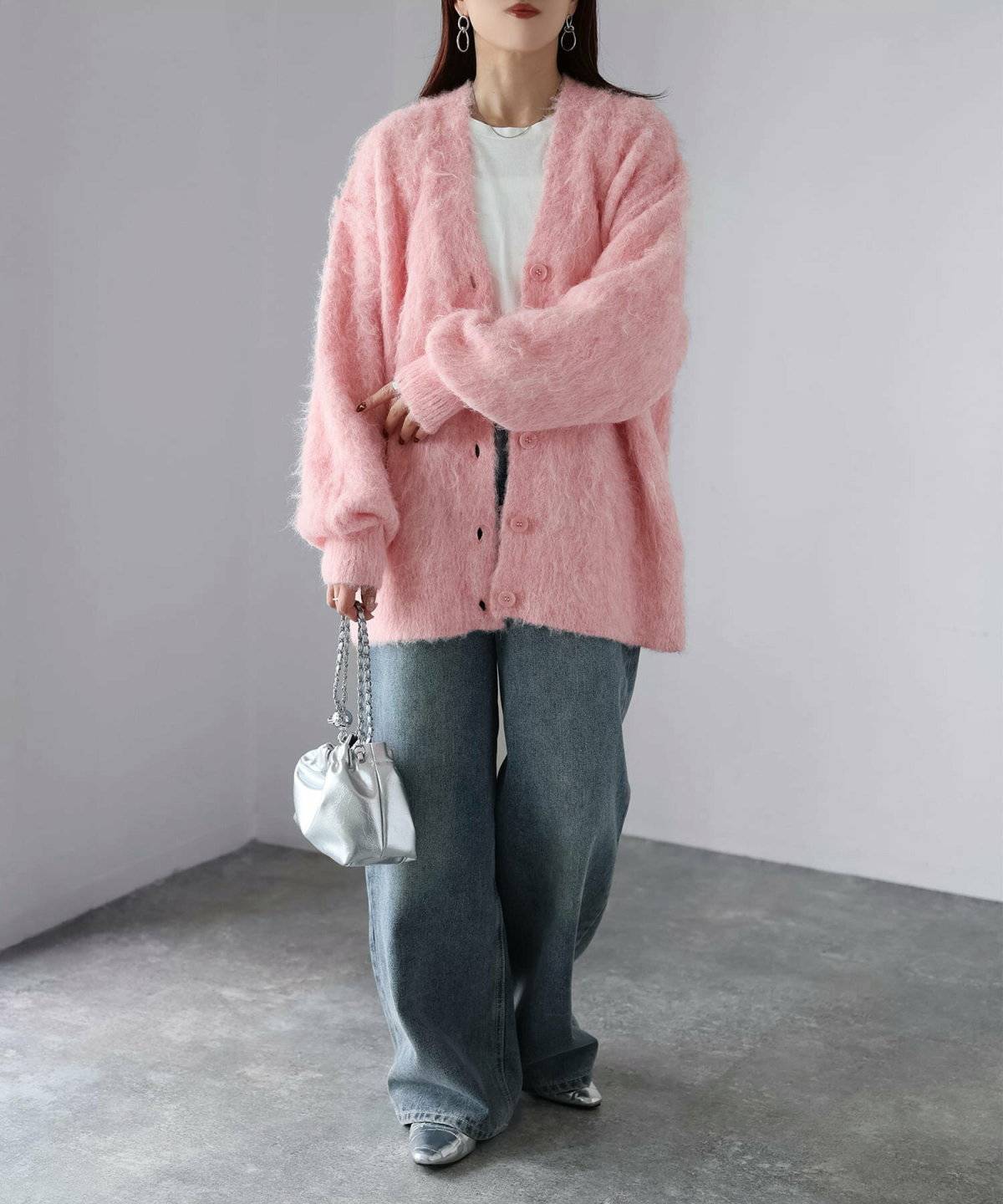 ピンクのカーディガンにデニムを合わせた女性