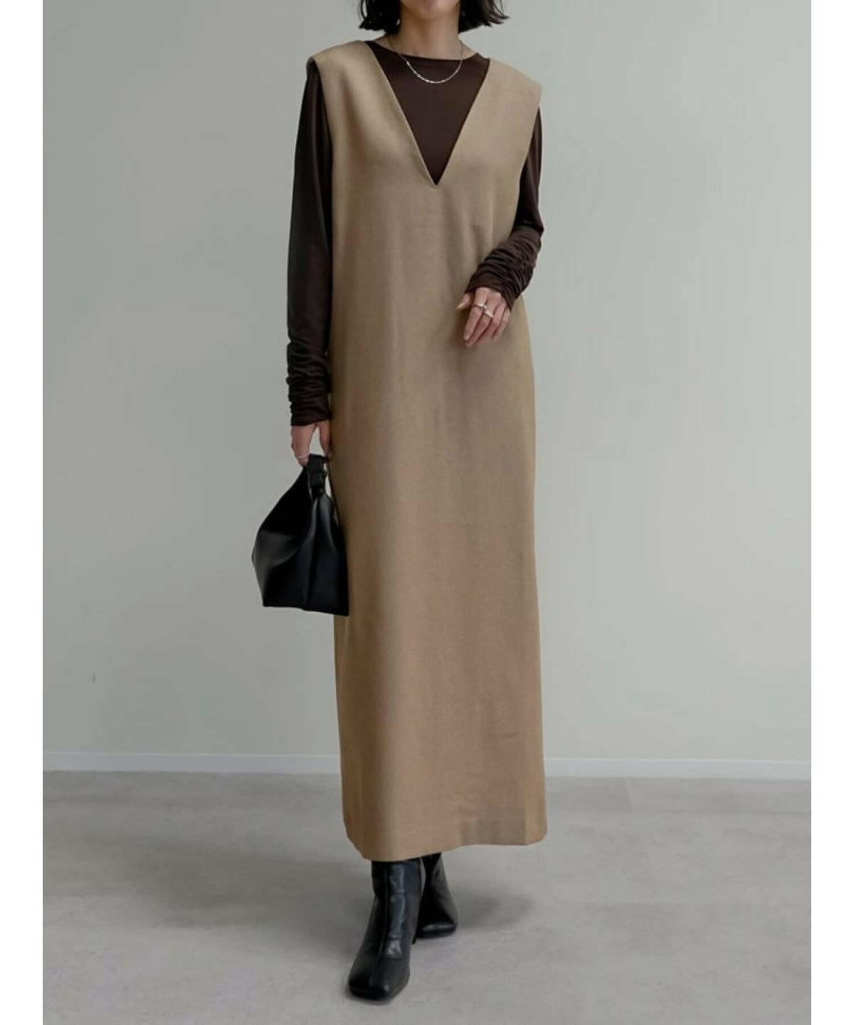 ベージュのトップスにブラウンのワンピースを重ねた女性