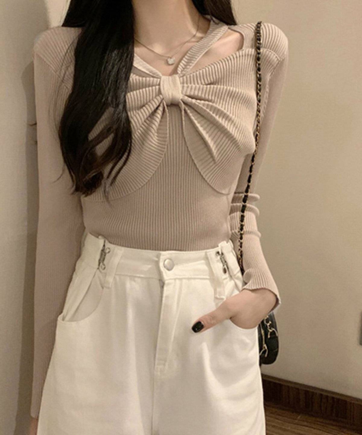 ベージュのニットに白パンツを合わせた女性