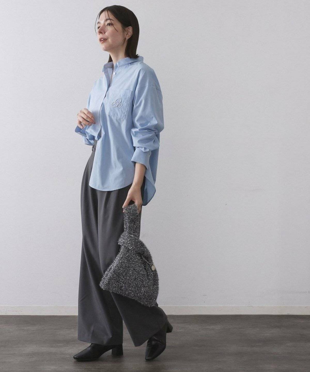 ブルーのシャツにグレーのパンツを合わせた女性