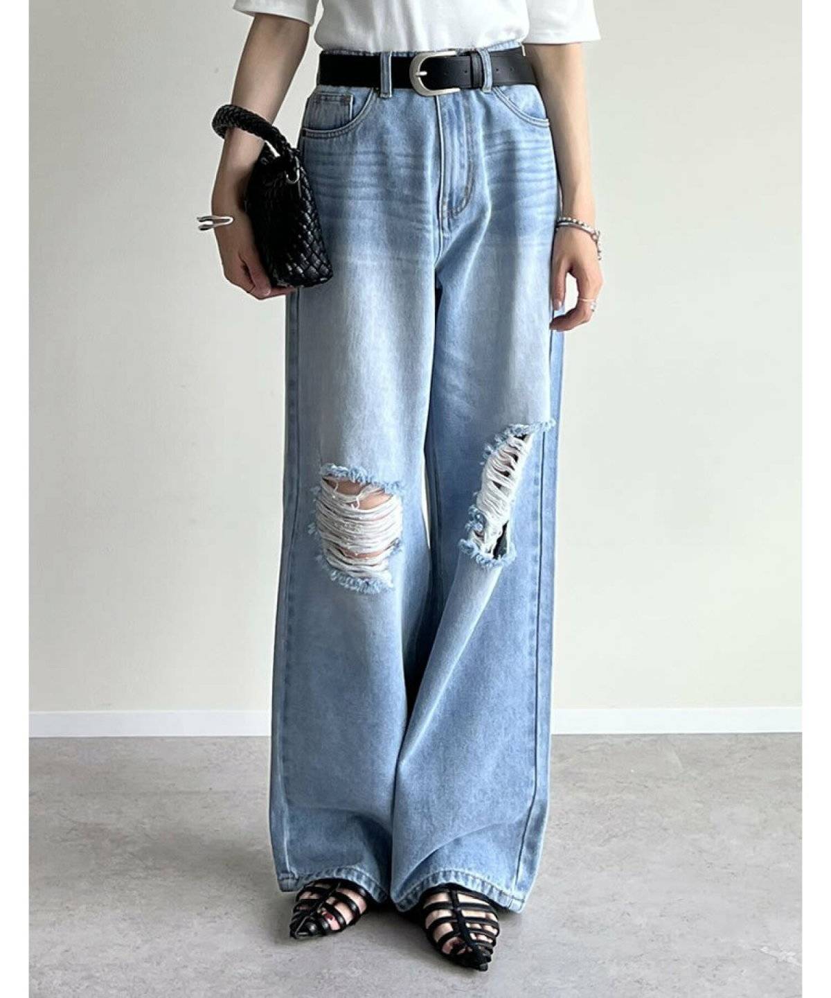 白Tシャツにグレーのベストを重ねてデニムを穿いた女性