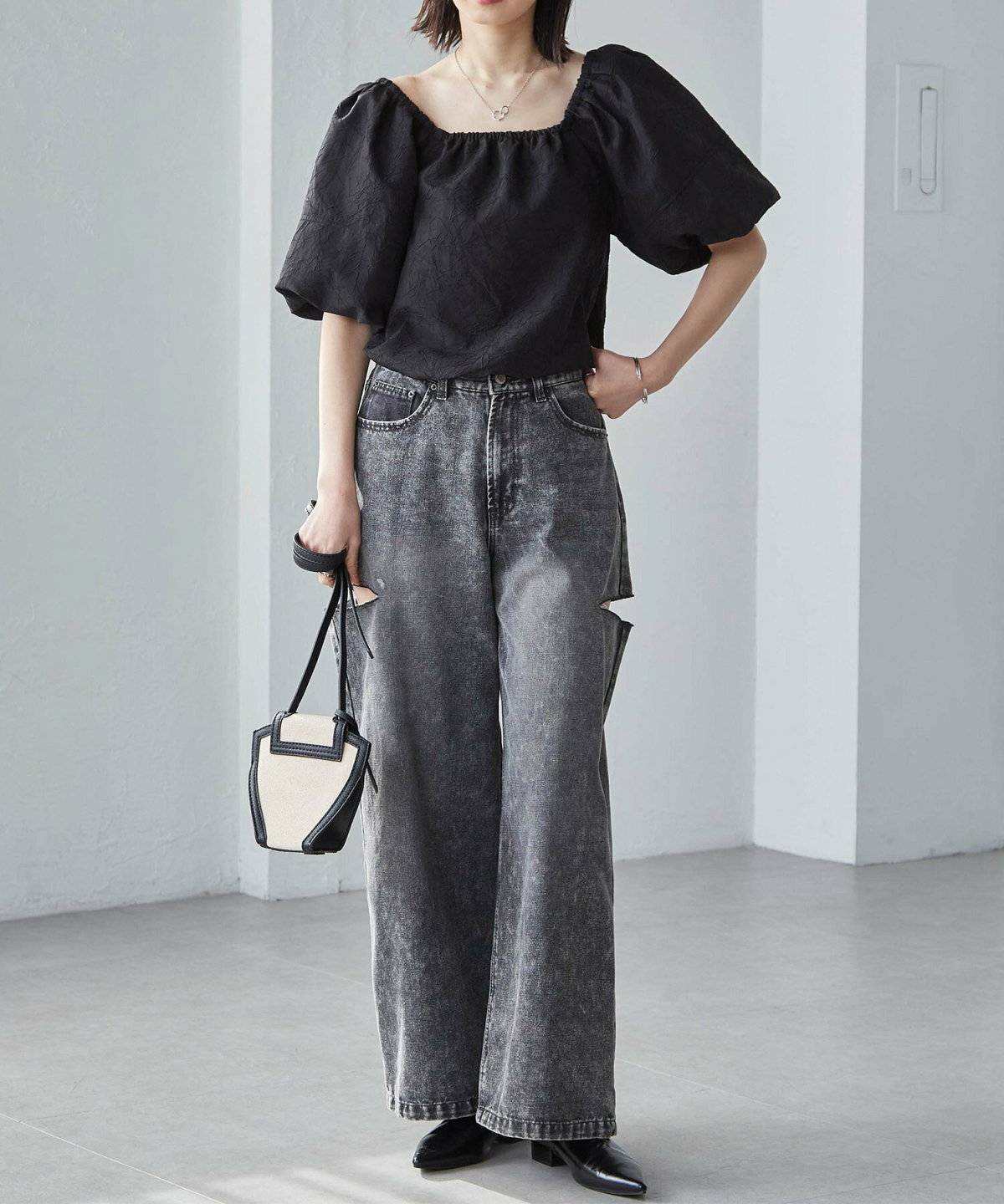 黒ブラウスにデニムを合わせた女性