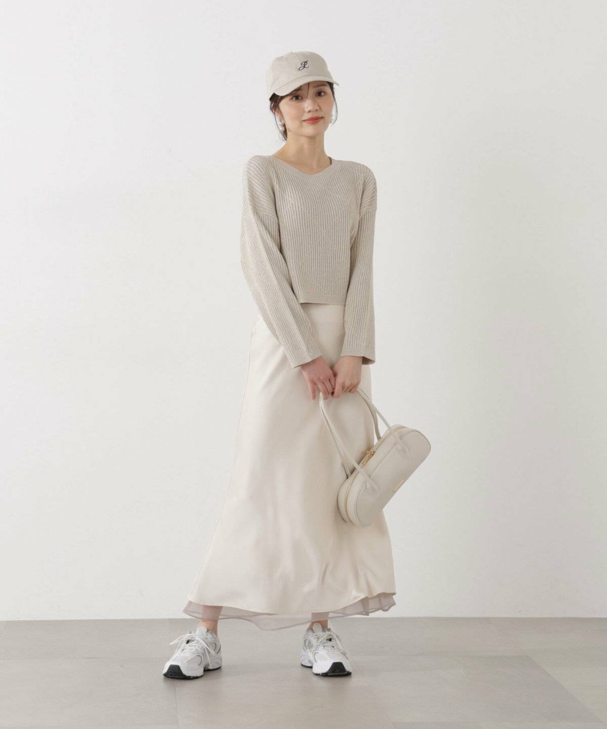 ベージュのシアーシャツに白のロングスカートを合わせた女性