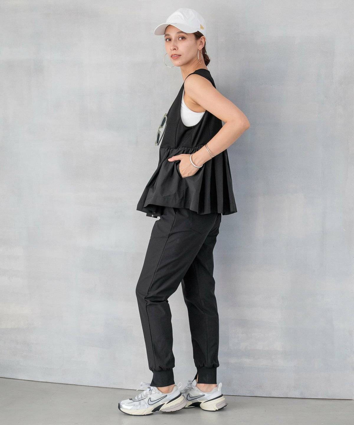 Tシャツにビスチェを重ねれ黒パンツを合わせた女性