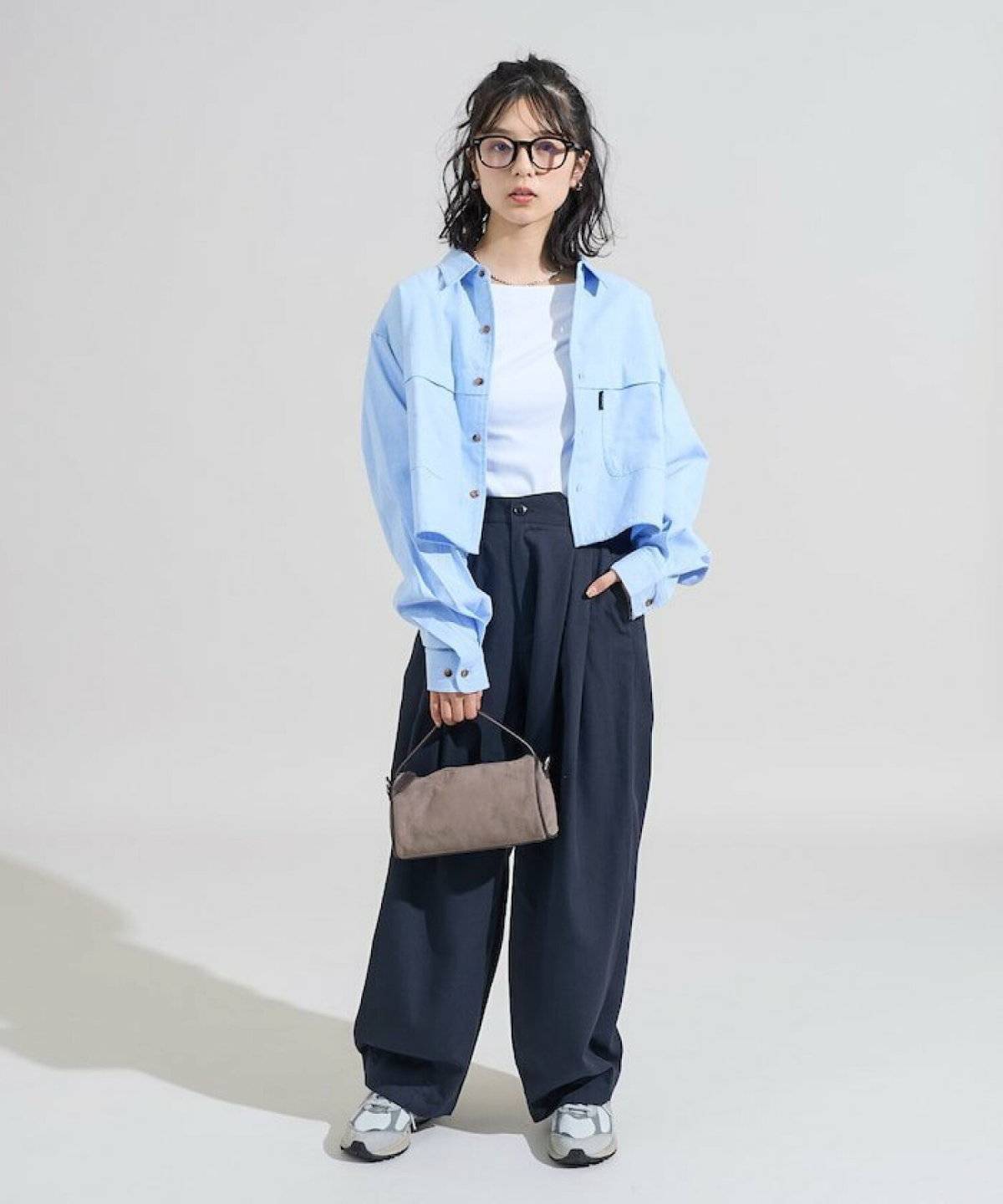 ブルーのシャツにグレーのパンツを合わせた女性