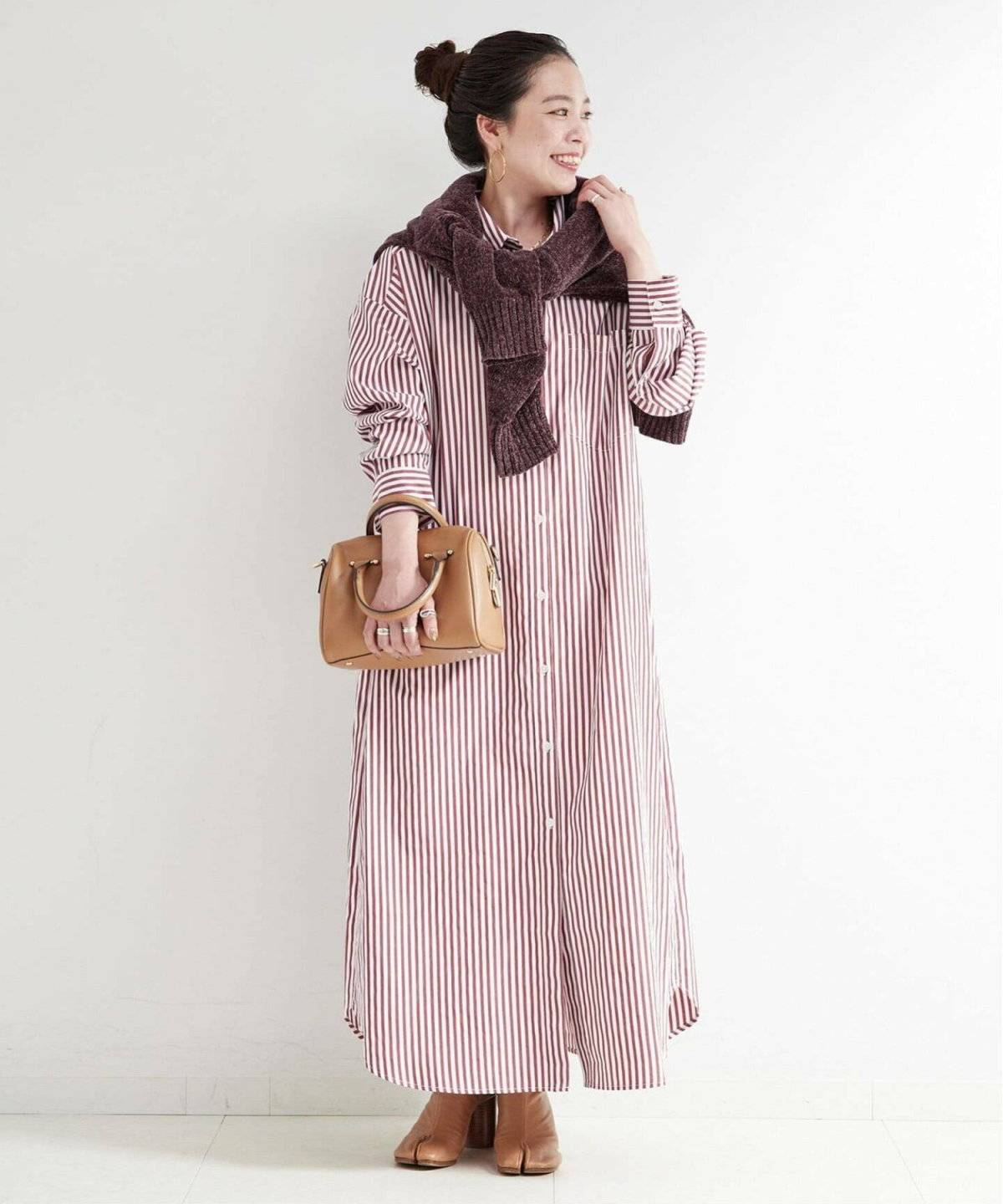 ストライプ柄のシャツワンピースにカーディガンを肩掛けした女性