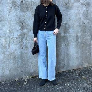  黒カーディガンにデニムパンツを合わせた女性 