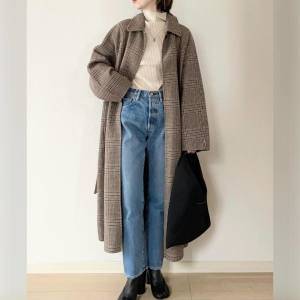  ベージュのコートにデニムパンツを合わせた女性 