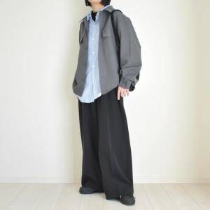  グレージャケットに黒パンツを合わせた女性 