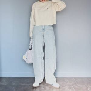 白トップスにデニムパンツを合わせた女性 