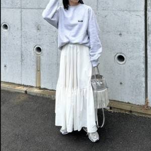  グレーのスウェットに白スカートを合わせた女性 