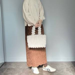  白トップスにブラウンのスカートを合わせた女性 