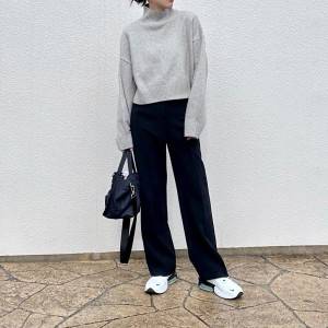  グレーのニットに黒パンツを合わせた女性 