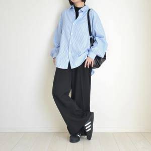  ストライプ柄のシャツに黒パンツを合わせた女性 