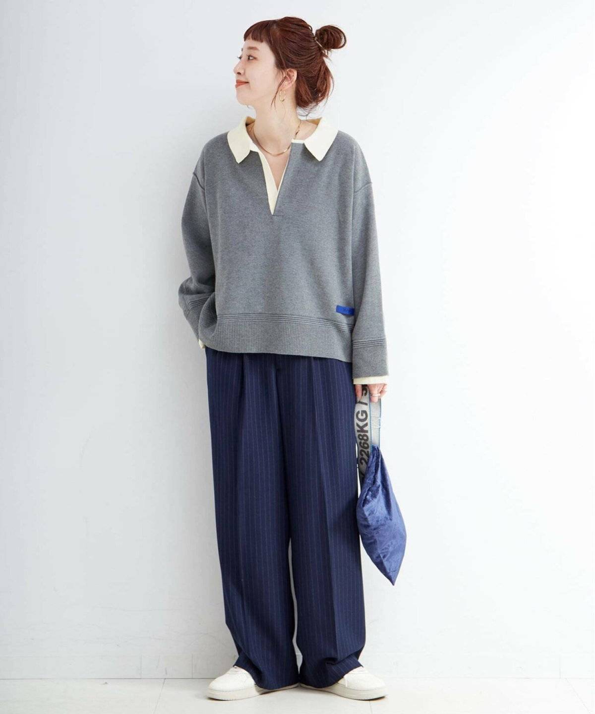 ニットにストライプ柄パンツを合わせた女性