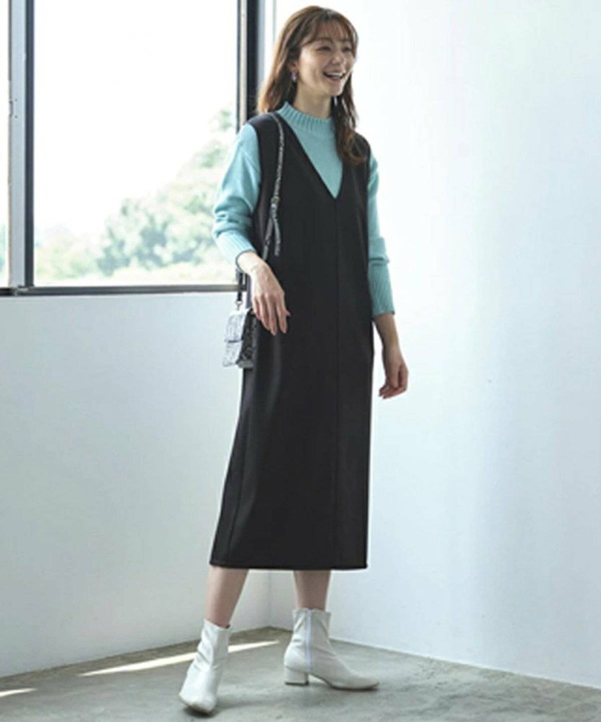 ニットに黒のジャンパースカートを合わせた女性