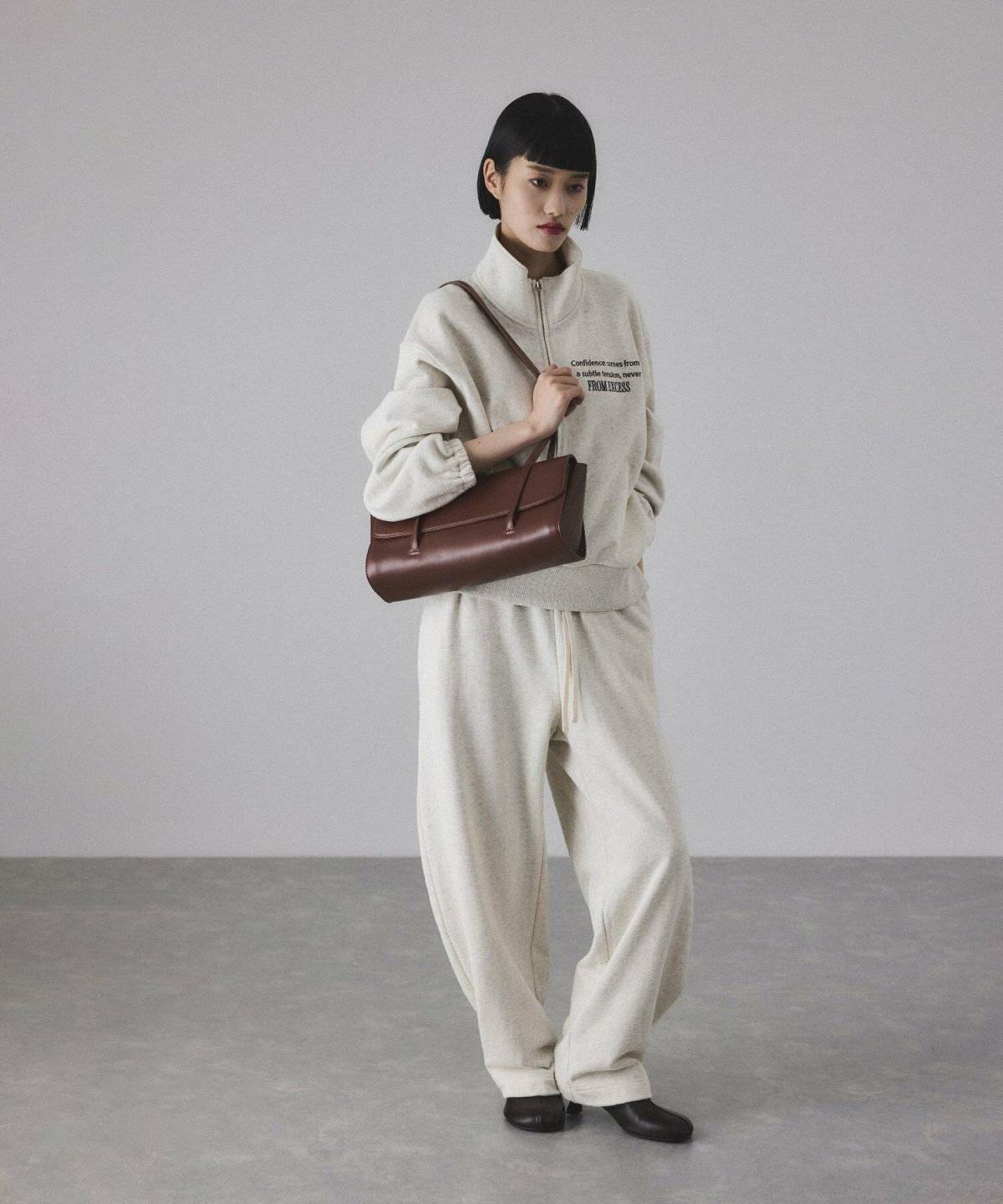 ベージュのスウェットに白パンツを合わせた女性