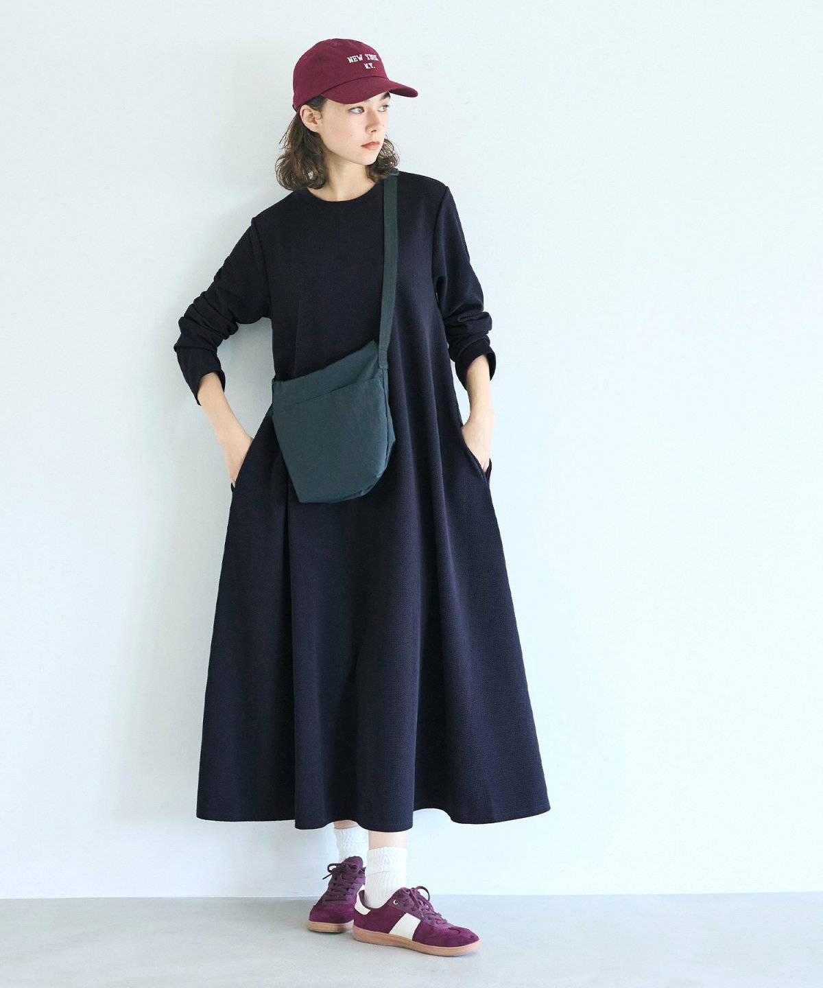 黒ワンピースにブラウンのジャケットを持った女性