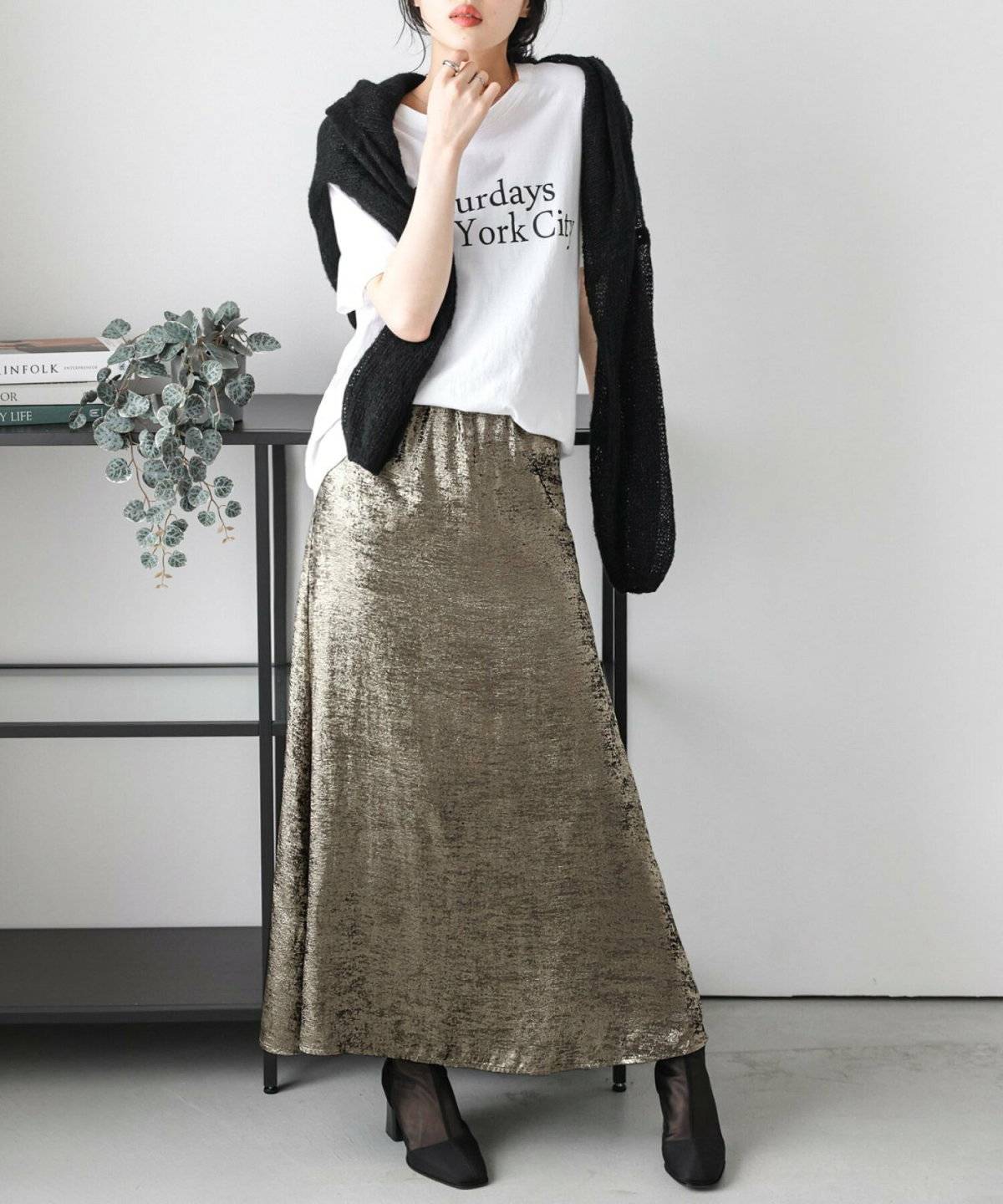 白トップスにゴールドのスカートを合わせた女性