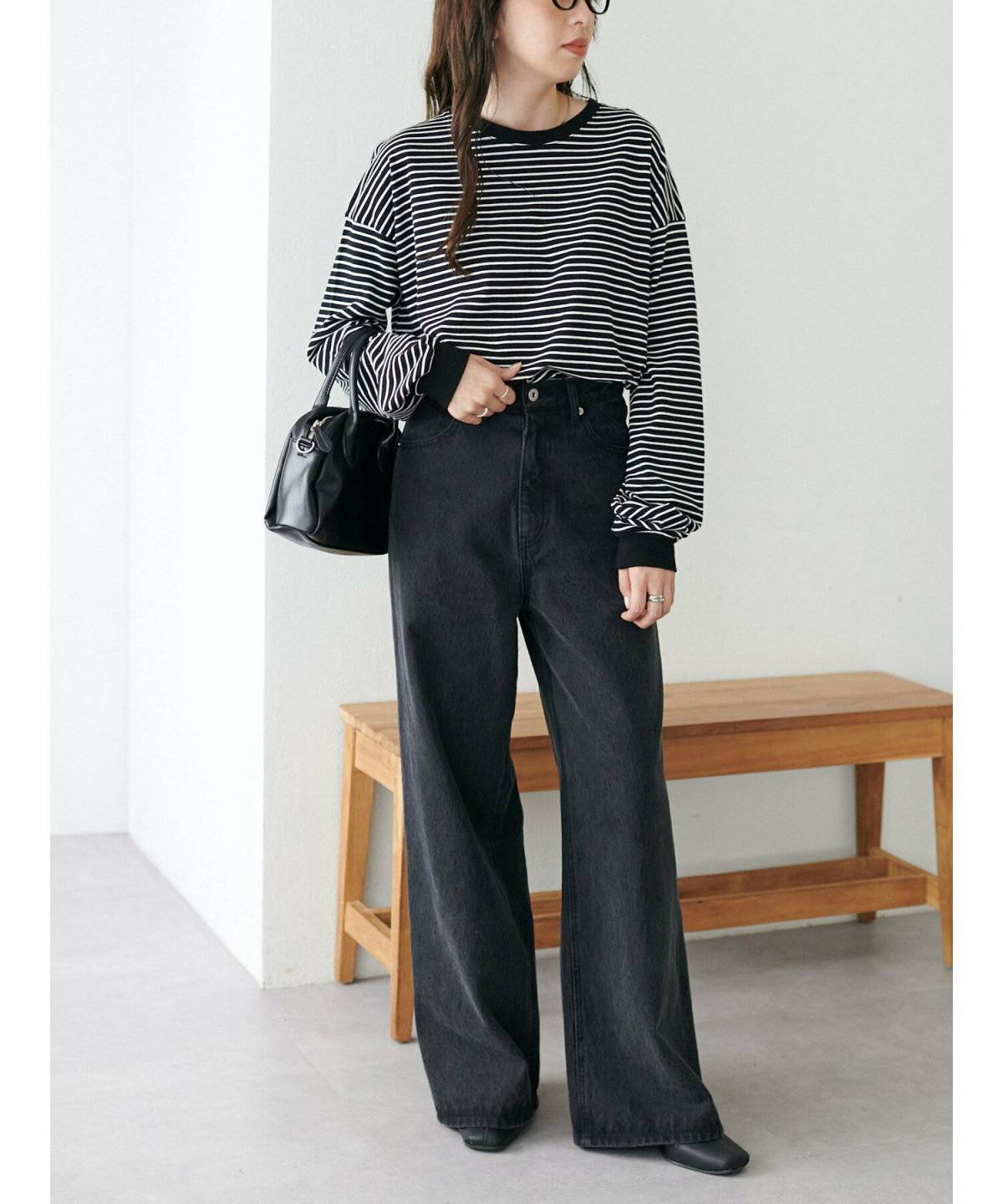 ボーダー柄のトップスに黒パンツを合わせた女性