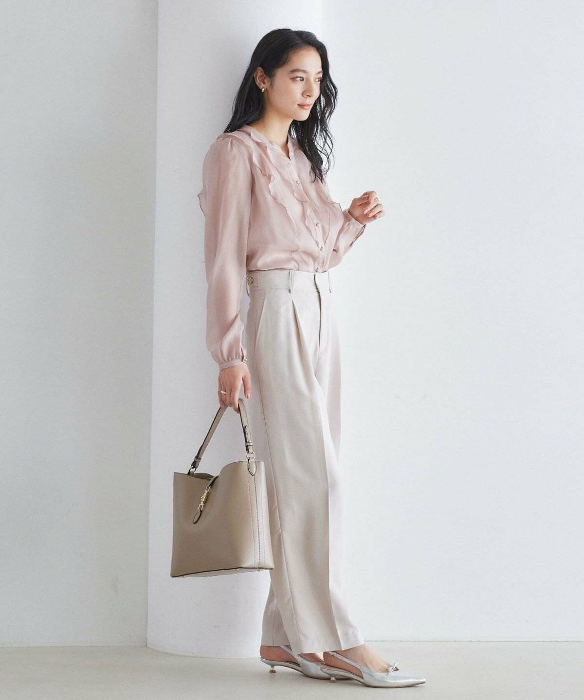 ピンクのブラウスに白パンツを合わせた女性