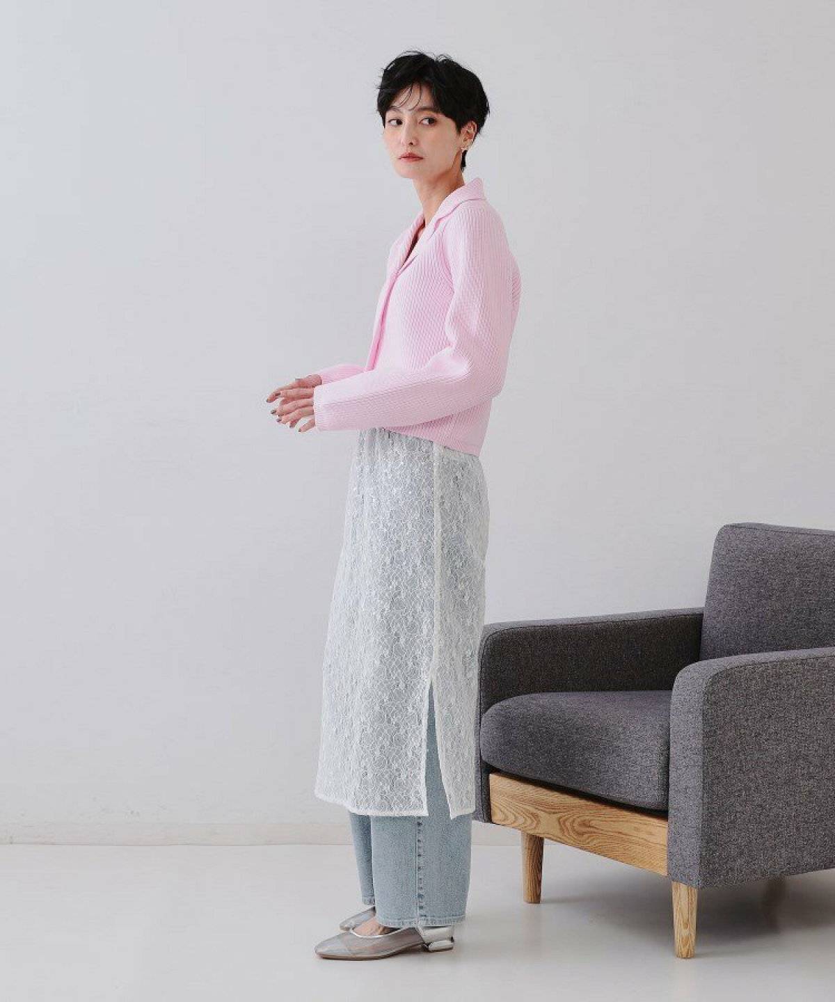 ブルーのカーディガンに白スカートとデニムを合わせた女性