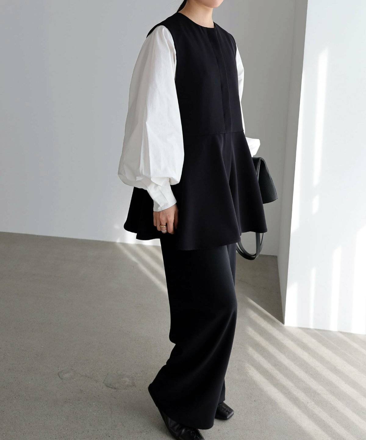 モノトーンコーデにベストを重ねた女性