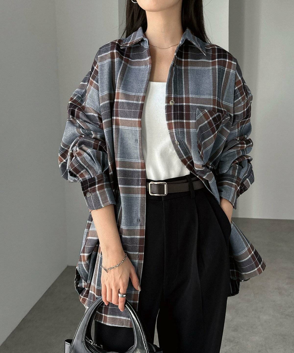 グレーのチェック柄シャツに黒パンツを合わせた女性