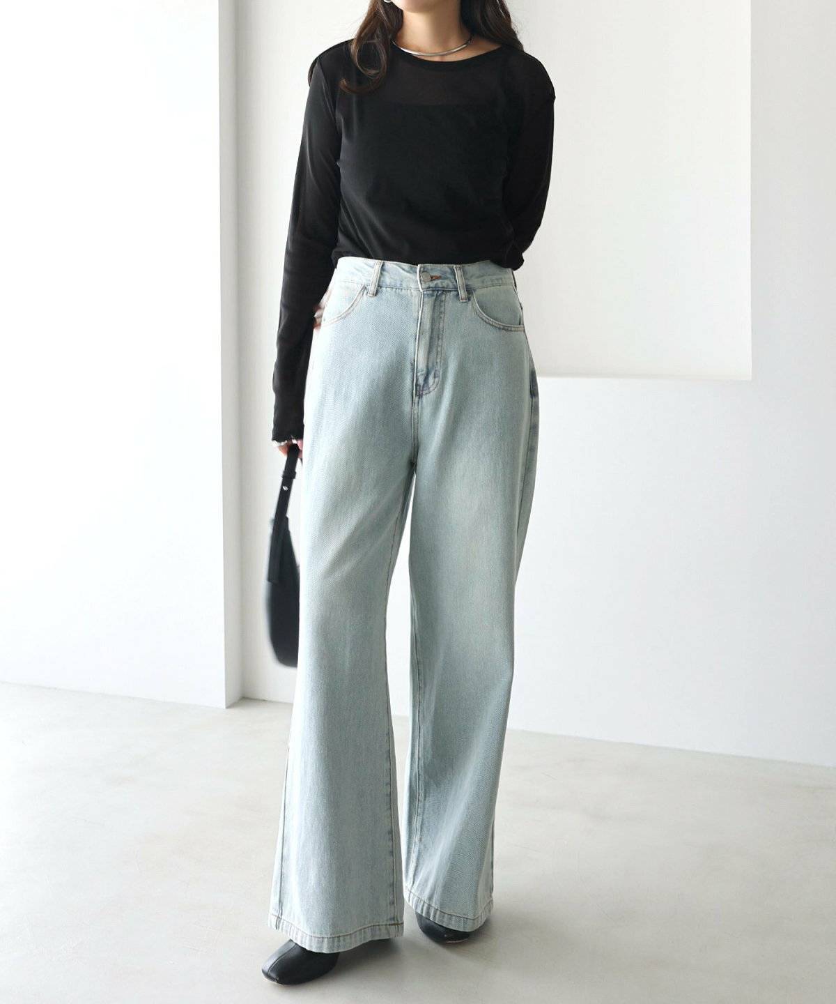 黒のシアートップスにデニムを合わせた女性