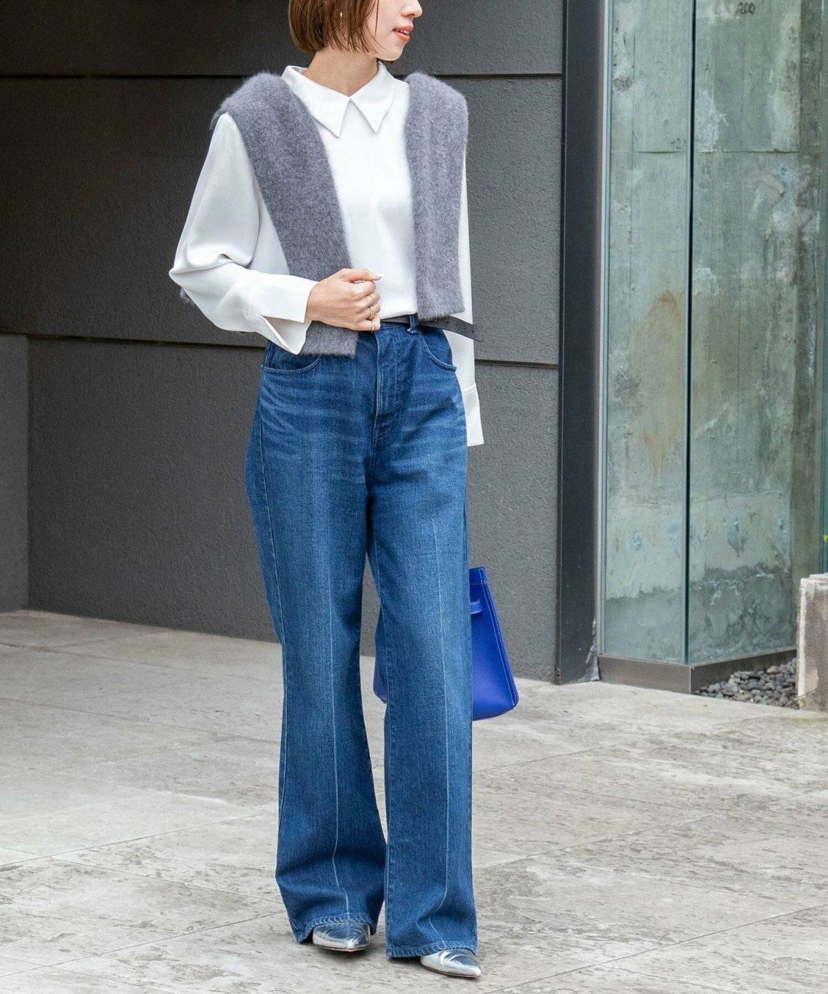 シャツにデニムを合わせてカーディガンを肩掛けした女性