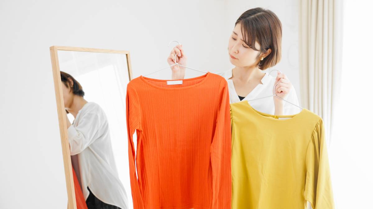 鏡の前で服選びをしている若い女性