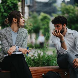  外のベンチで話す男女 