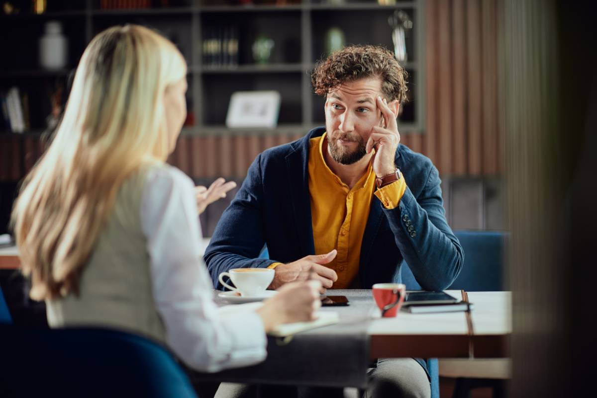 同僚の女性の話を険しい表情で聞く男性